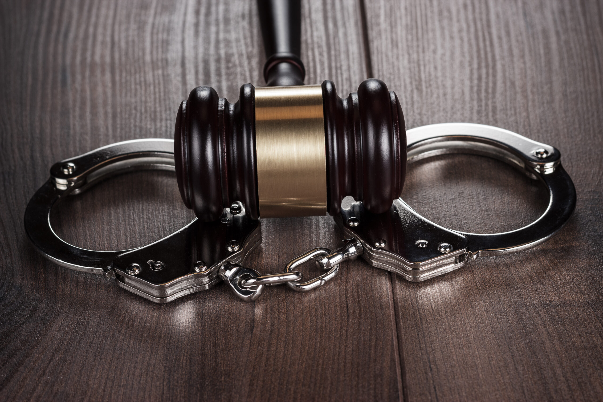 Handcuffs and keys on a wooden table representing the legal services of a Poway criminal defense attorney.